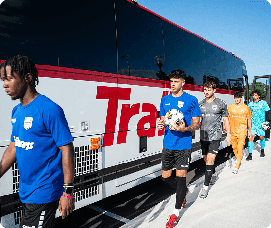 Players walking beside a Trailways bus